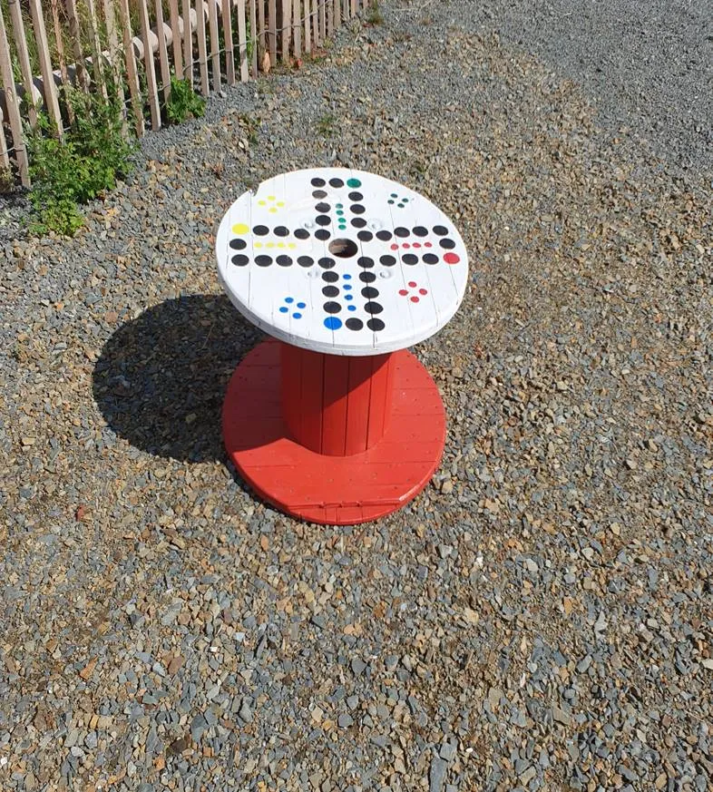 Ein runder Spieltisch aus einer Kabeltrommel, bemalt als Spielfeld für „Mensch ärgere dich nicht